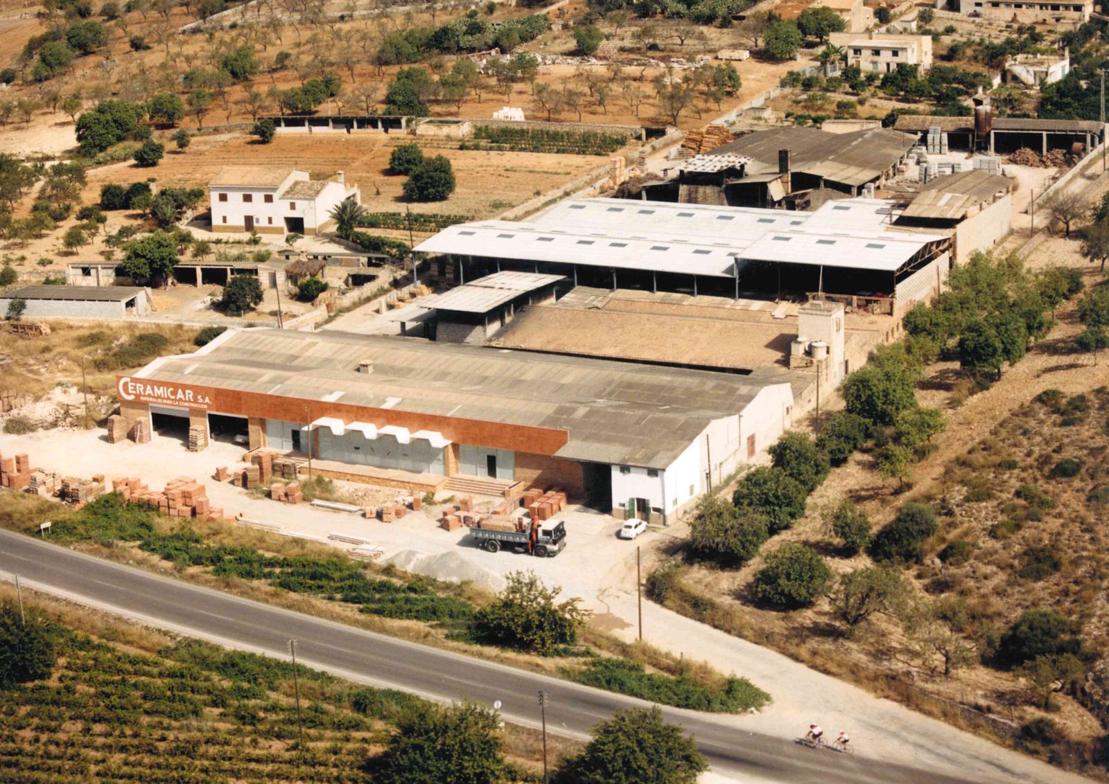 Vista aèria de les naus del magatzem vora la carretera, als anys 90.